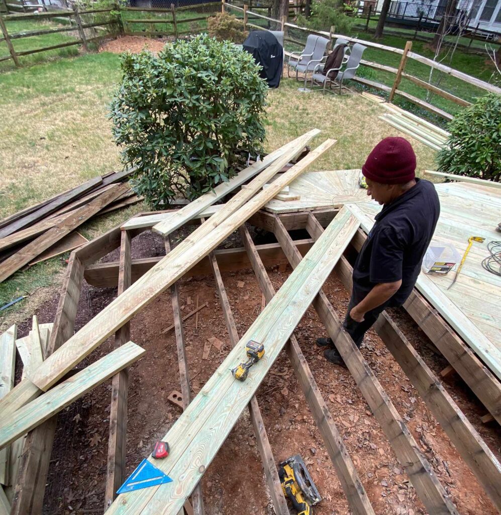 Contractors laying the solid wooden framework and joists for a new outdoor living space, demonstrating the structural expertise of a top deck builder Gaithersburg MD.