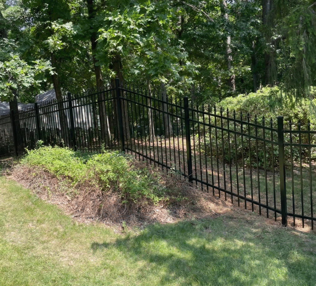 A black ornamental aluminum fence installed in a wooded Maryland backyard, showcasing the best fence material for Maryland 2026 for durability and elegance.
