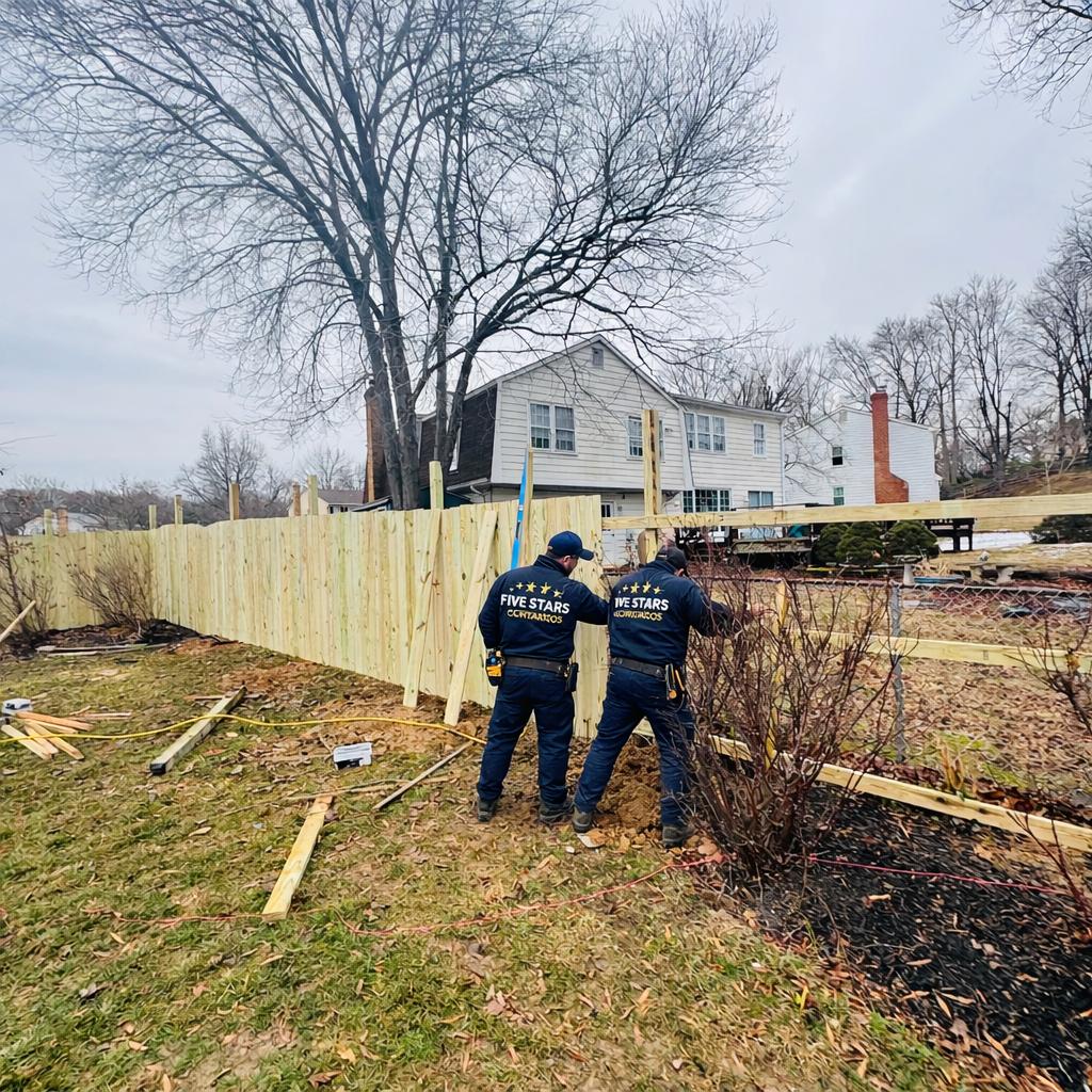 Contractors cutting materials for a white vinyl privacy fence installation in the snow, completing an Emergency Fence Repair Maryland 2026 project.