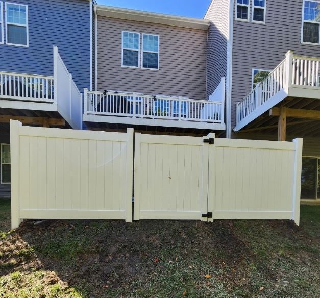 A newly installed white vinyl privacy fence with a double gate, representing a top choice for the best fence material for Maryland 2026 due to its low maintenance.